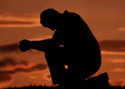 žmogus meldžiasi ant vieno kelio