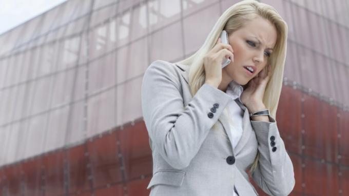 Moteris su ADHD klausosi kažkokio telefono ir pyksta priešais aukštą pastatą